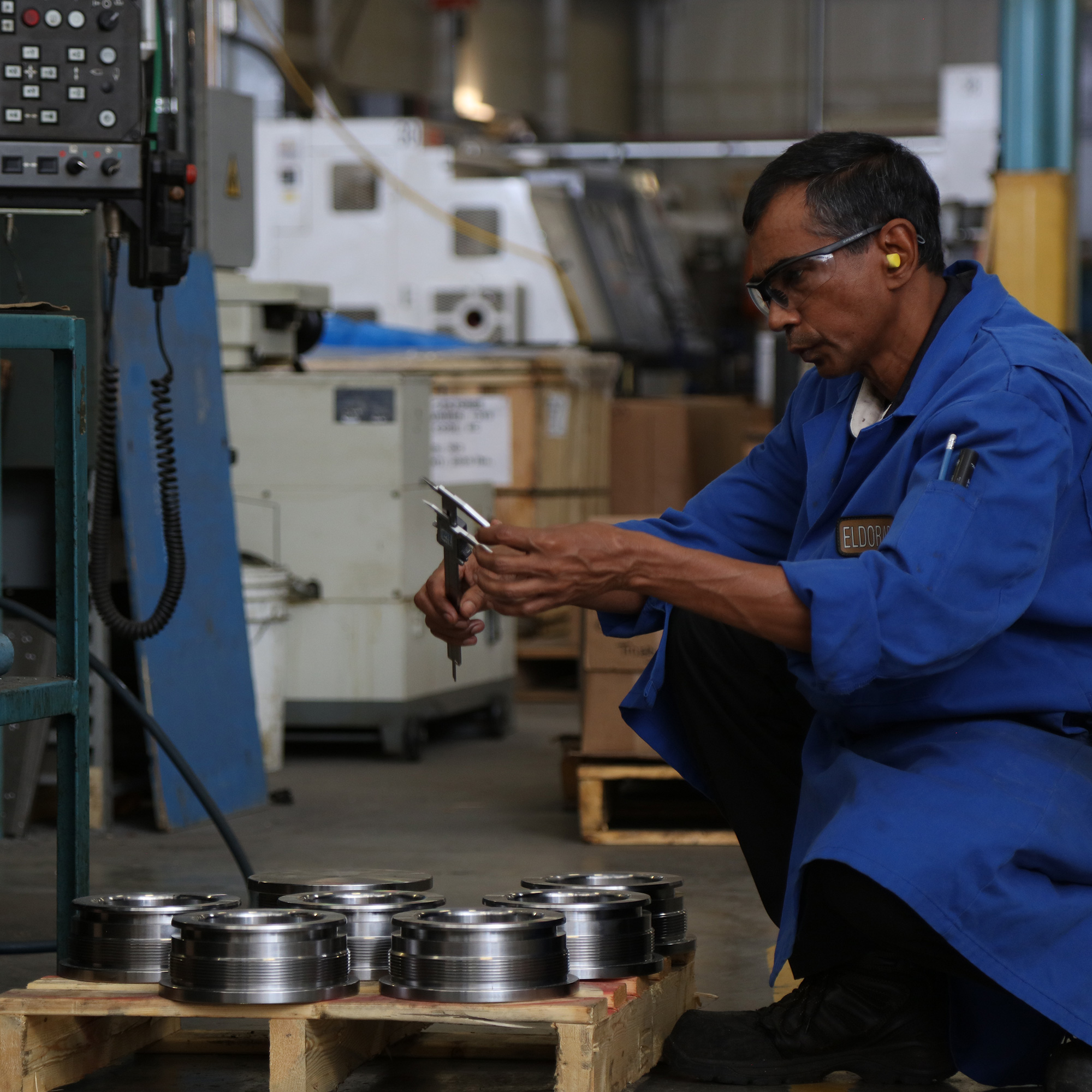 a crouching employee holds a caliper and measures a component