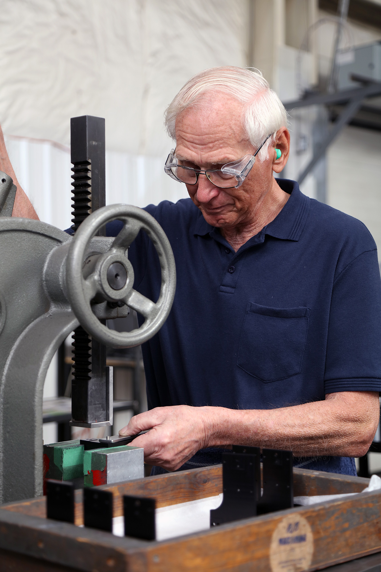 an employee wearing safety glasses and earplugs operates a machine