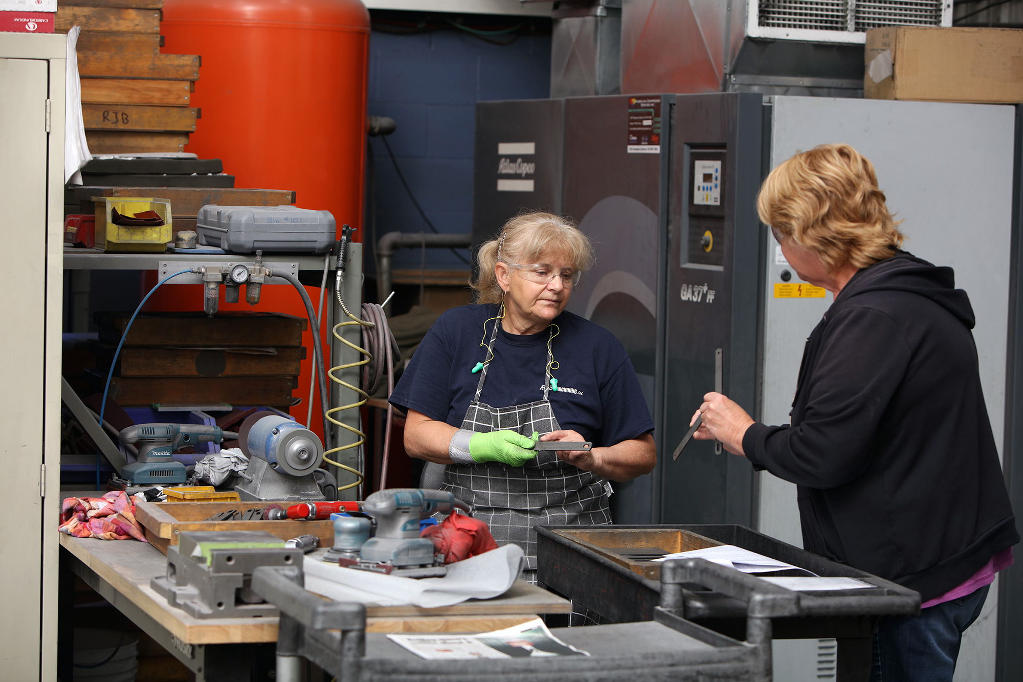 two employees stand at a table inspecting components