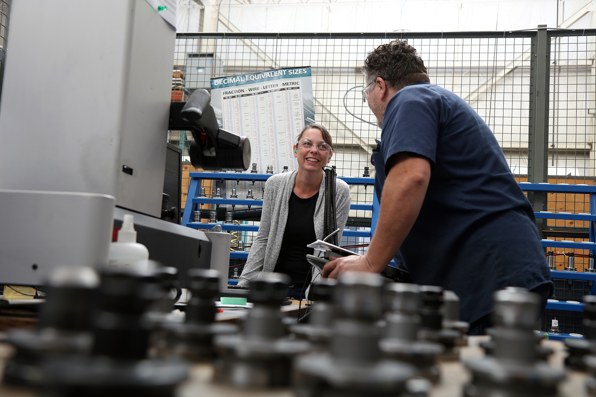two employees standing by a machining centre, laughing and talking