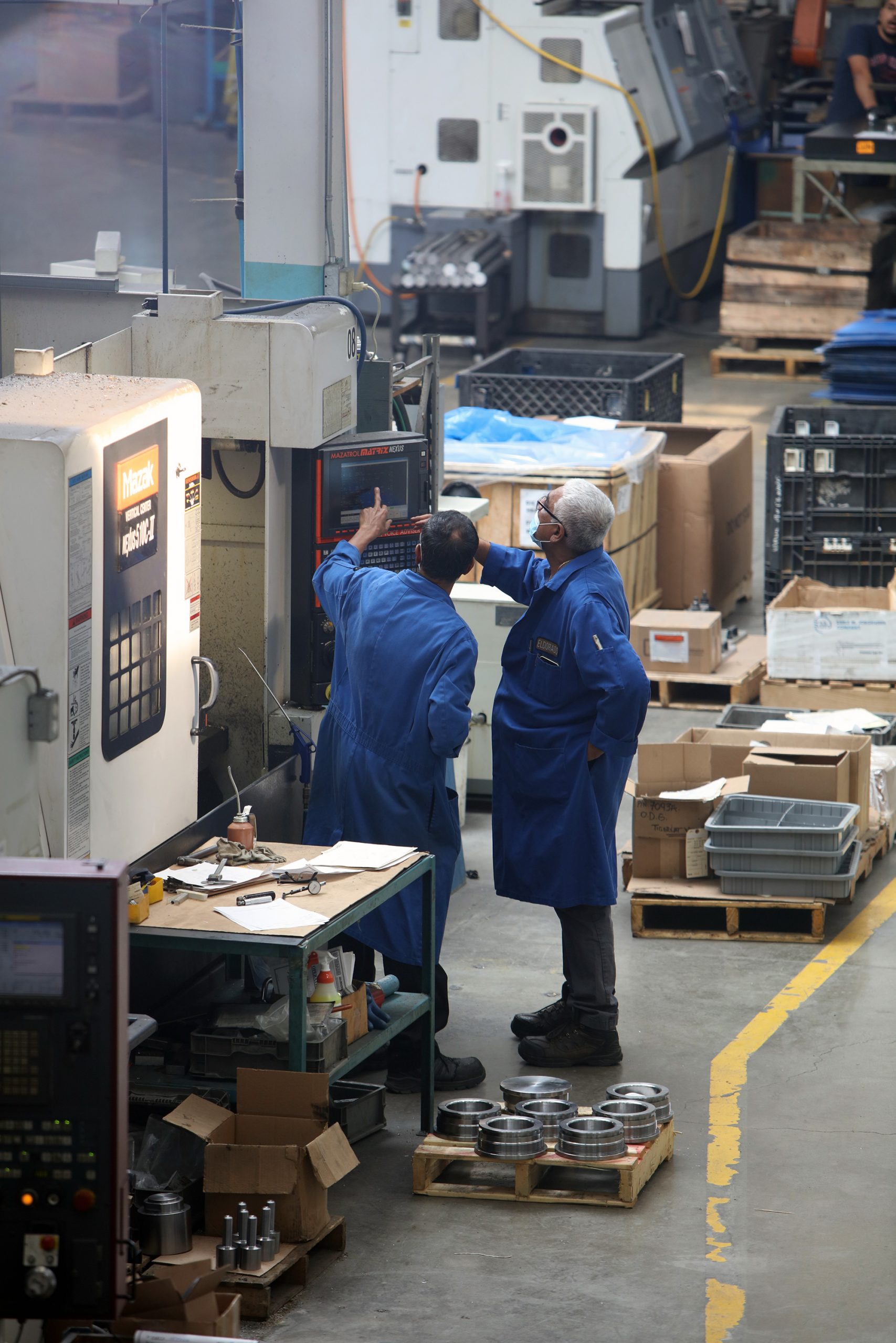 two employees pointing at the controls of a machining centre