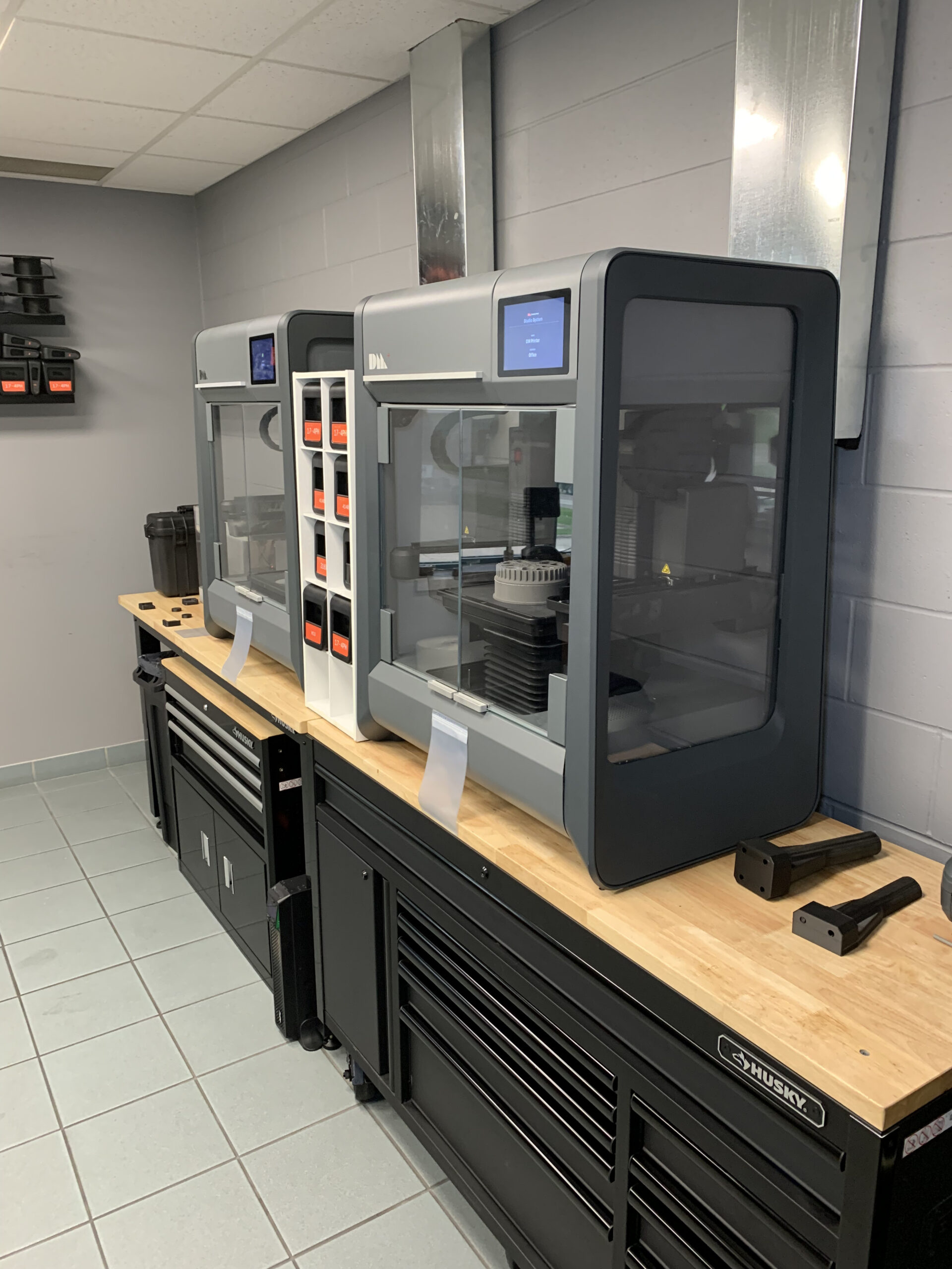 a 3D printer and other tools organized on a counter in a workshop setting.