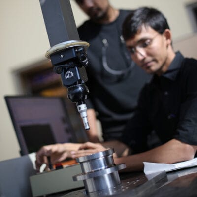 close up of a machine probe system with an employee in the background operating it